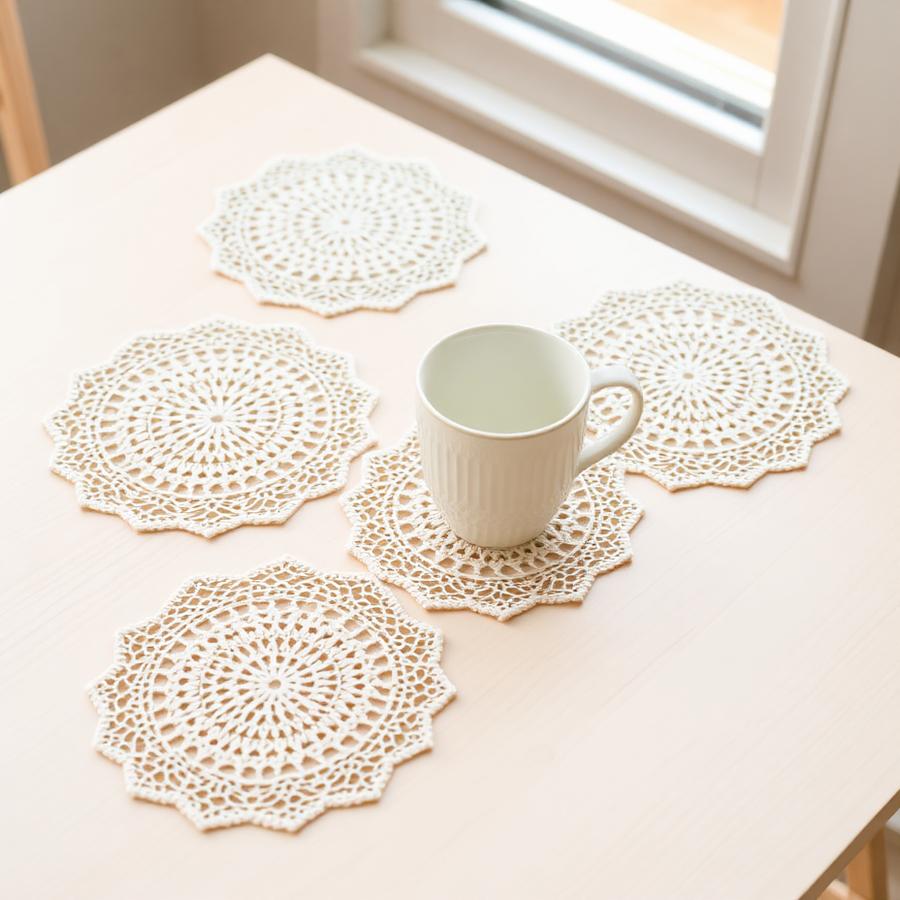 Set of cream crochet lace doily coasters on a wooden table